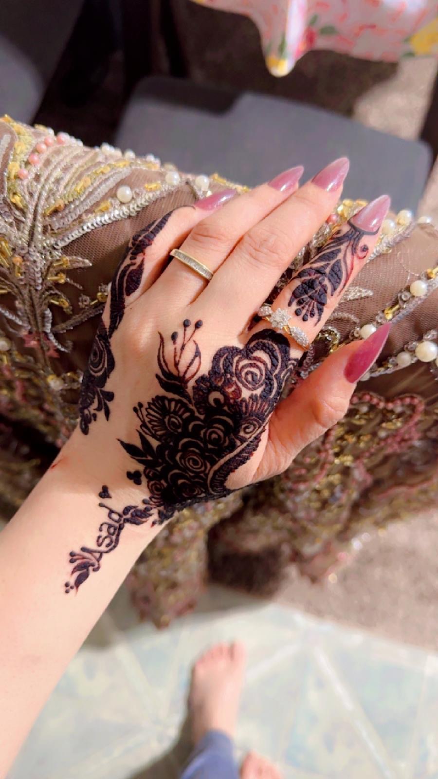 Dark black henna florals on hand