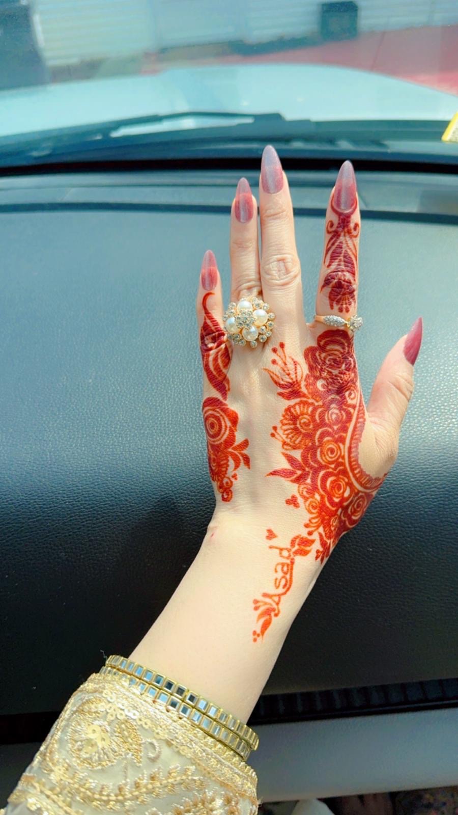 Vibrant red henna roses on hand